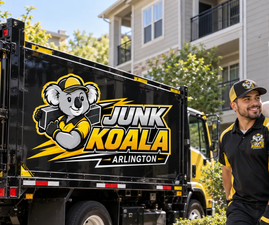 The Junk Koala Arlington dump truck parked below the balconies of an Arlington apartment community with a crew member alongside